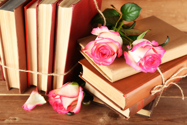 Tied books with pink roses on wooden table, closeup - Foto, Imagen