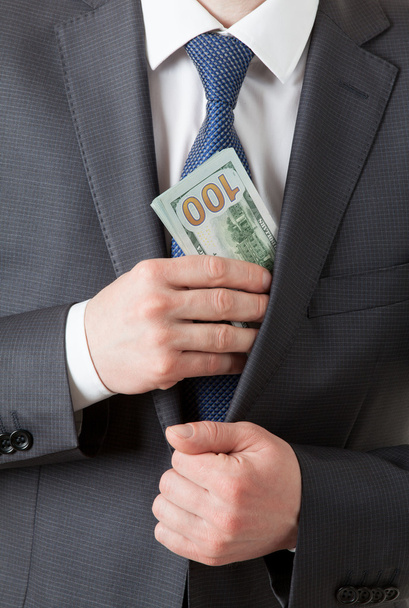 Businessman holding dollars/putting dollars in a pocket - 写真・画像