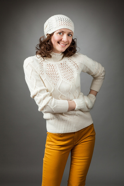Smiling young woman posing in a studio wearing in a sweater and  - Фото, изображение