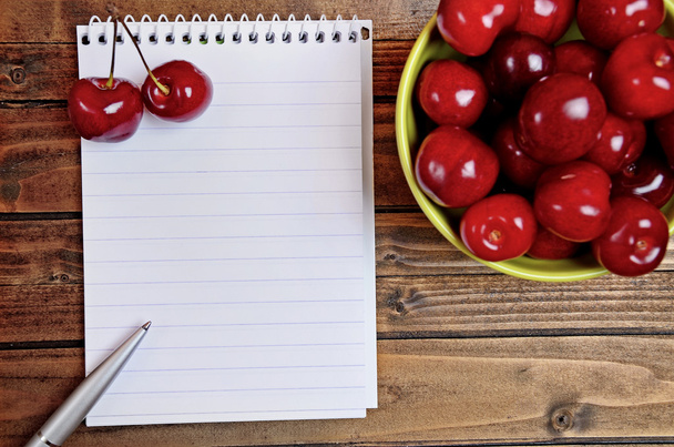 Notebook and green bowl with cherry - Fotoğraf, Görsel