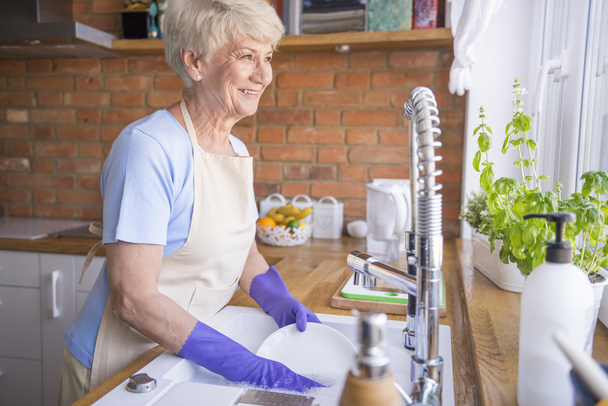 зріла жінка миє тарілки на кухні
 - Фото, зображення