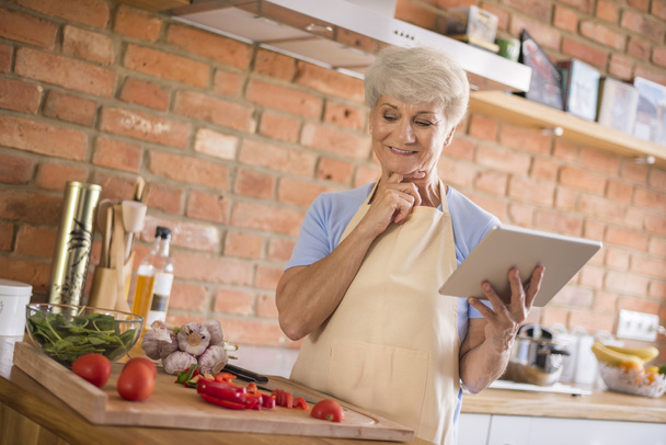 mature woman looking recipe on tablet - Foto, Imagem