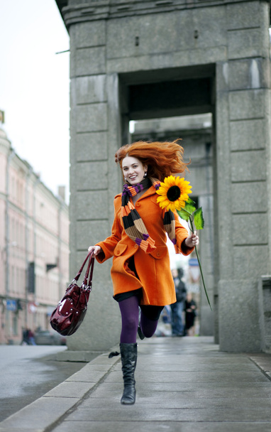 Pretty girl walking with a sunflower city - Фото, зображення