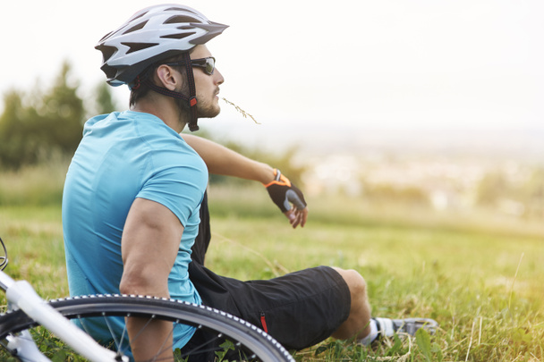 νεαρός άνδρας με ποδήλατο, κάθονται στο χόρτο - Φωτογραφία, εικόνα