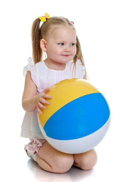 Beautiful little girl on her knees with the ball in his hands - Фото, зображення