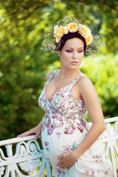 Beautiful pregnant girl with a wreath of flowers - Photo, image