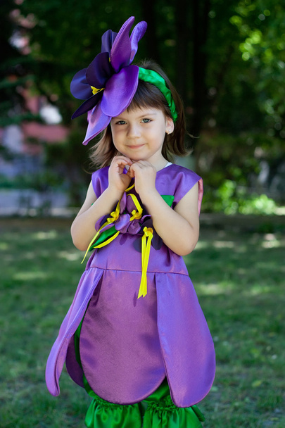 La niña con un traje de flor violeta sonríe en el bac
 - Foto, imagen