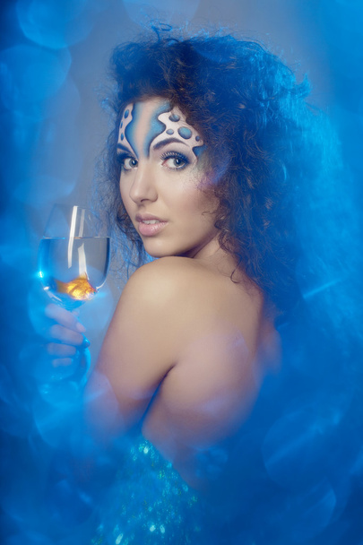 Girl with makeup, with a fish in a glass in her hand - Photo, image