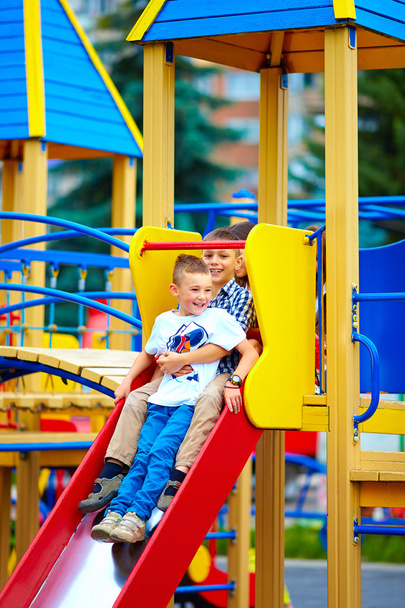 group of happy kids sliding in colorful playground - Foto, Imagem