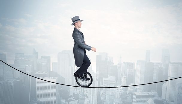Brave guy riding a monocycle on a rope above cityscape - Photo, Image