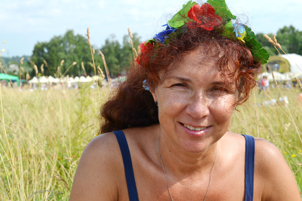 Happy beautiful redhead woman with flowers in her hair in her fourties smilling outdoors - Photo, Image