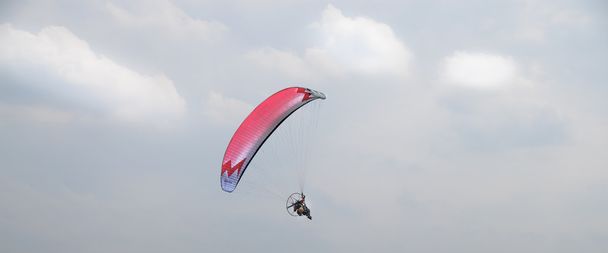 моторизованный параплан, летящий в небе
 - Фото, изображение
