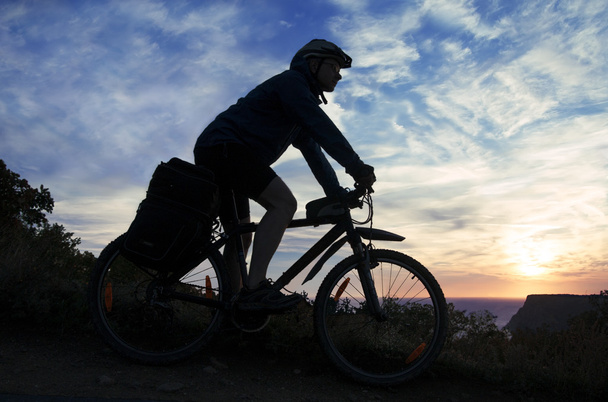Silhouette eines Radfahrers auf dem Hintergrund des bewölkten Himmels bei s - Foto, Bild