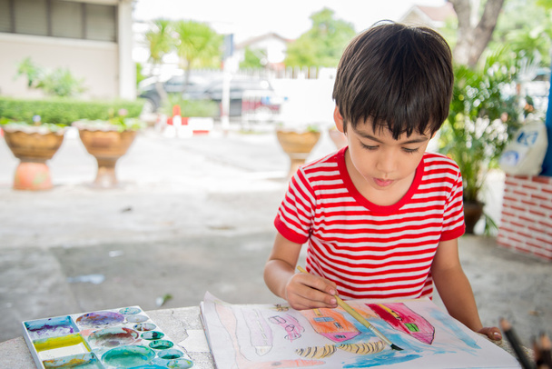 Niño pequeño dibujo de imagen en la mesa al aire libre
 - Foto, Imagen