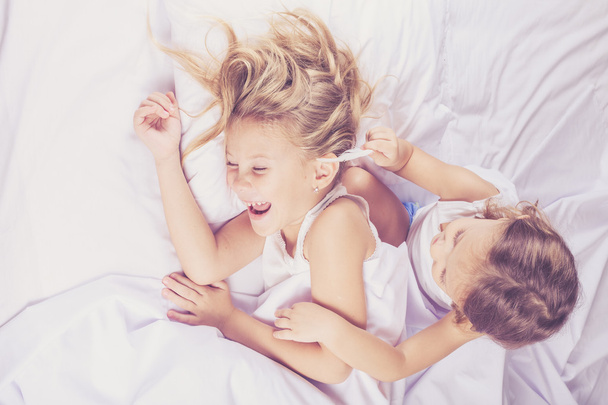 Lovely brother and sister lying in bed at home. - Foto, Bild