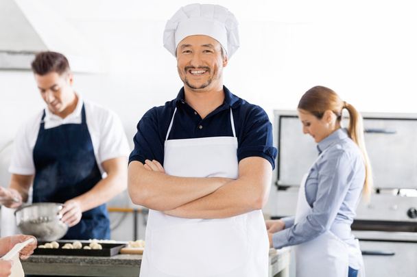 Confident Chef Standing Arms Crossed While Colleagues Working In - Foto, Imagem