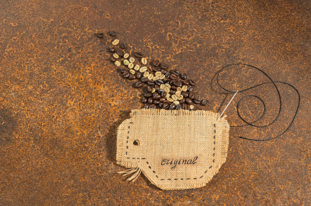 針とワイヤーのさびで覆われたテーブルの上に置かれたコーヒー豆のジュートで縫い付けカップ. - 写真・画像