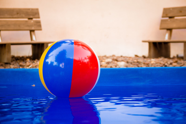 Colorful beach ball floating in pool - Foto, afbeelding