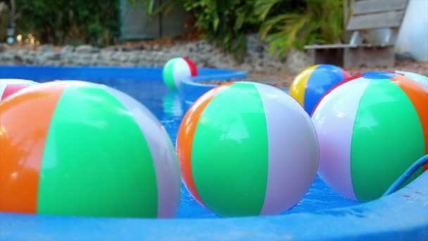 Coloridas bolas de playa flotando en la piscina en cámara lenta
 - Imágenes, Vídeo