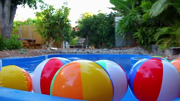 Bolas coloridas de praia flutuando na piscina em câmera lenta
 - Filmagem, Vídeo