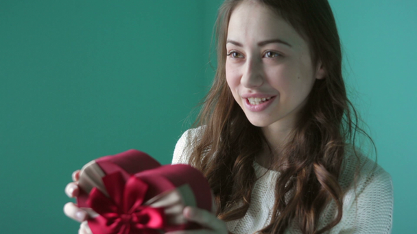 Hermosa joven sonriente mujer con un regalo en forma de corazón en sus manos
 - Metraje, vídeo
