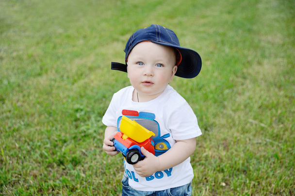 baby boy in a cap and a toy car in the hands of - Photo, image