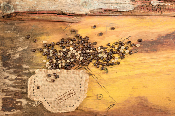 Une tasse cousue en jute avec des grains de café placés sur une vieille table en bois
. - Photo, image