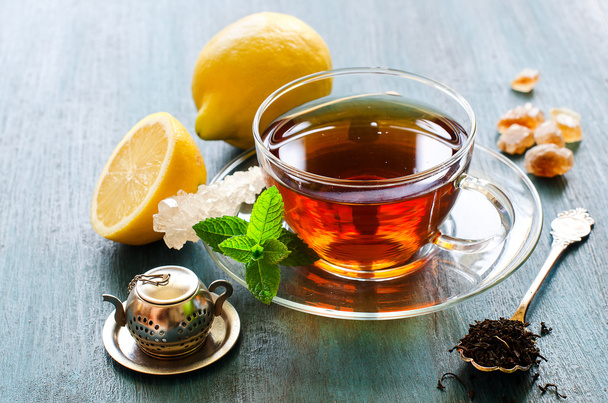 Cup of black tea with mint, lemon and chrystal sugar - 写真・画像
