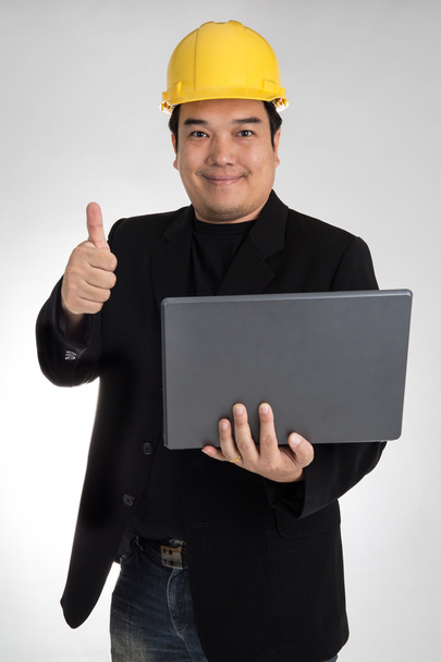 Retrato de asiático sorrindo segurando laptop com capacete de segurança
 - Foto, Imagem