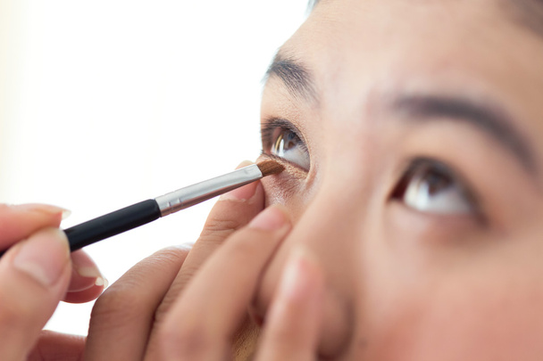 eye makeup with brush on pretty woman face - 写真・画像