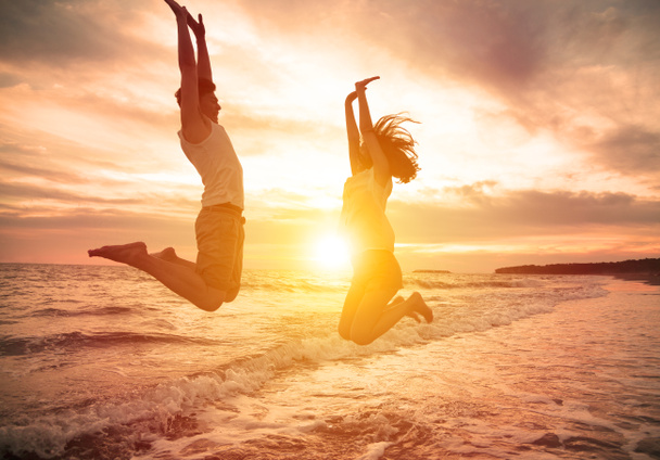 nuori onnellinen pari hyppäämällä rannalla
 - Valokuva, kuva