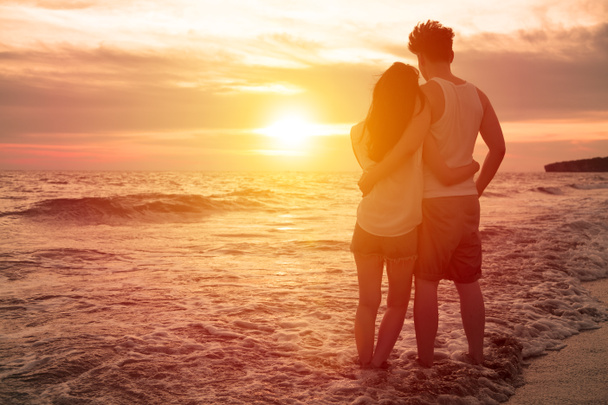 giovane coppia guardando il tramonto sulla spiaggia
 - Foto, immagini