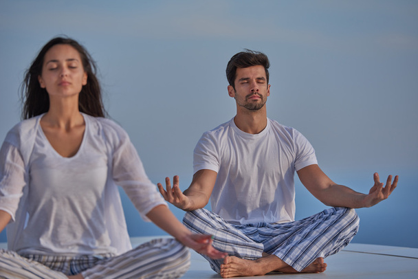 Young couple practicing yoga at home terrace - Foto, Imagem