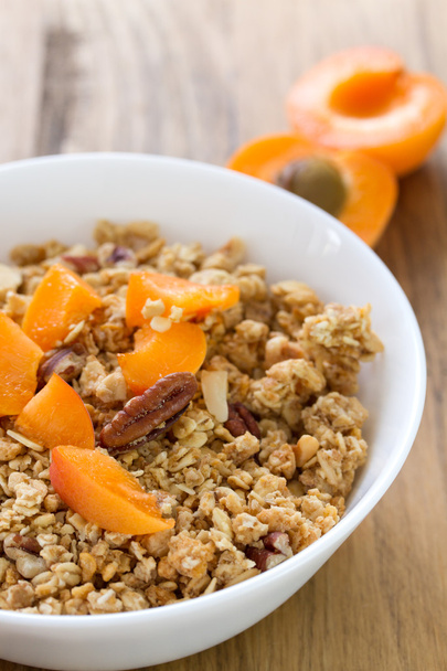 Granola with fruits and nuts in white bowl on brown wooden background - Φωτογραφία, εικόνα