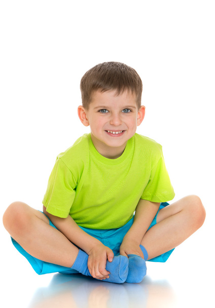 The child sits on the floor with folded legs under him - Photo, image