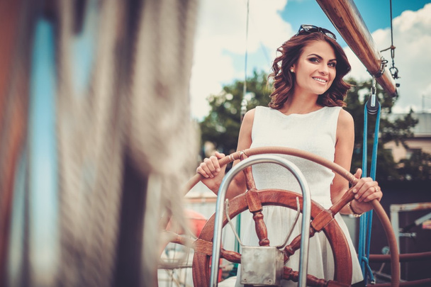 Stijlvolle rijke vrouw op een luxe houten regatta   - Foto, afbeelding