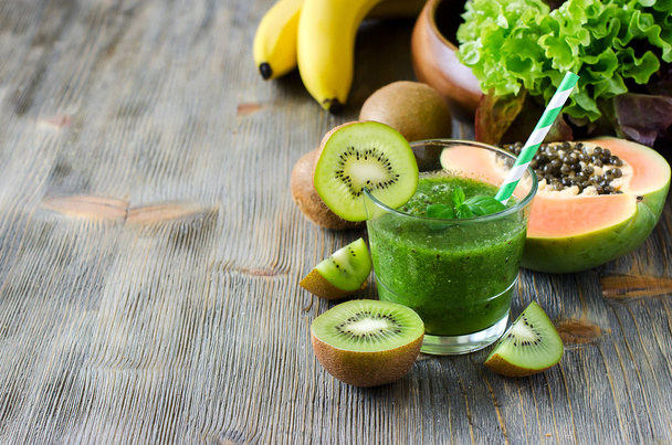 Green smoothie with kiwi, papaya and salad leaves copy space - Fotó, kép