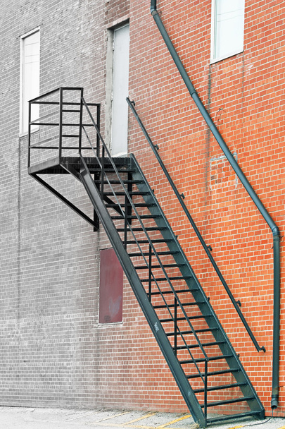 Metalowe schody pożarowe na zewnątrz budynku z cegły - Fotó, kép