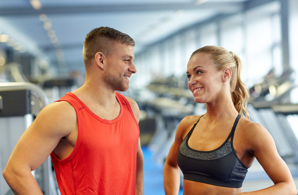 smiling man and woman talking in gym - 写真・画像
