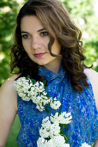 The girl in a blue dress holding a branch with white flowers - Foto, Bild