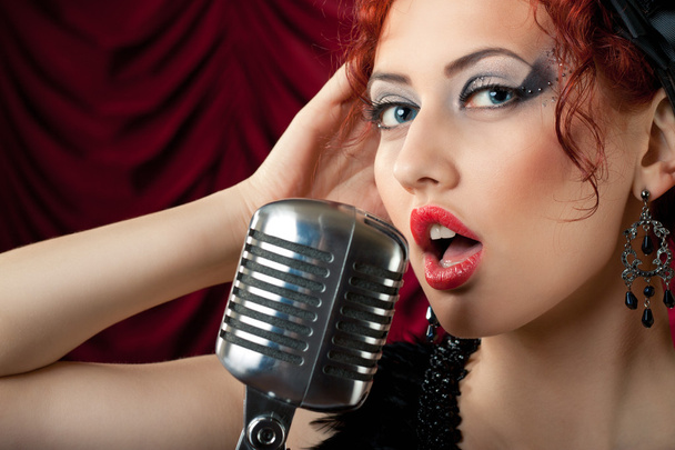 Beautiful redhead woman singing into vintage microphone - Фото, зображення