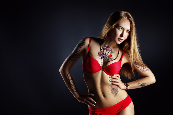 pretty girl with tattoo posing in red lingerie - Photo, Image