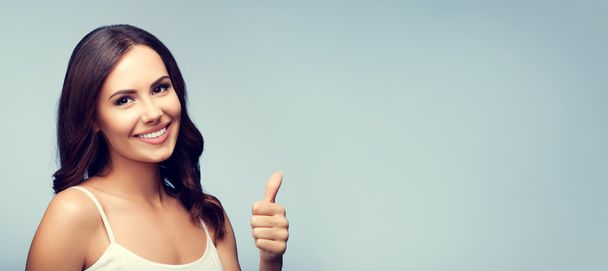 Portrait of happy brunette woman showing thumb up gesture, with  - Foto, imagen