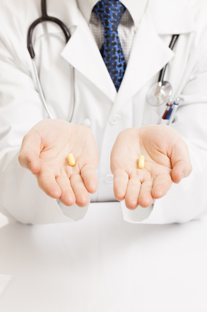 Doctor holding one pill on each palm - studio shot - Foto, afbeelding