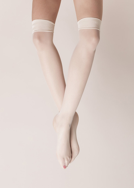Female legs with crossed feet wearing parisian stockings - Fotoğraf, Görsel