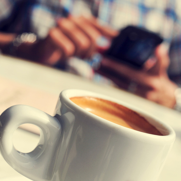 Mies, jolla on kuppi kahvia älypuhelimella terassilla
 - Valokuva, kuva