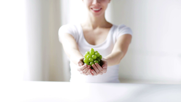 крупным планом молодая женщина показывает зеленый гроздь винограда
 - Кадры, видео