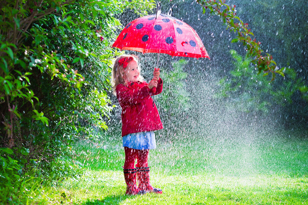 Little girl with umbrella playing in the rain - Photo, Image