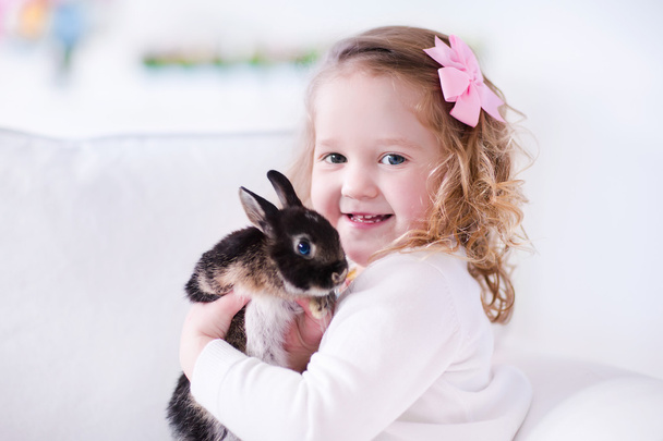 Little girl playing with a real pet rabbit - 写真・画像