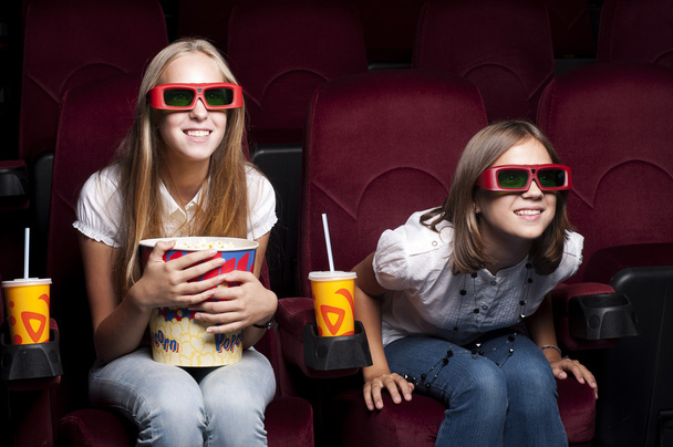 Two beautiful girls watching a movie at the cinema - Foto, Imagen